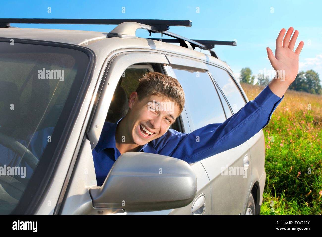 happy young man sit in the car and give salute gesture Stock Photo