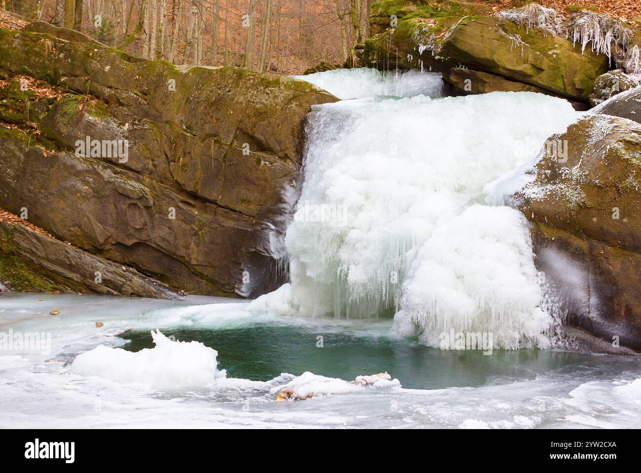 landscape with waterfall in winter. ice cold weather. frozen cascade on the water stream among the rocks in the forest Stock Photo