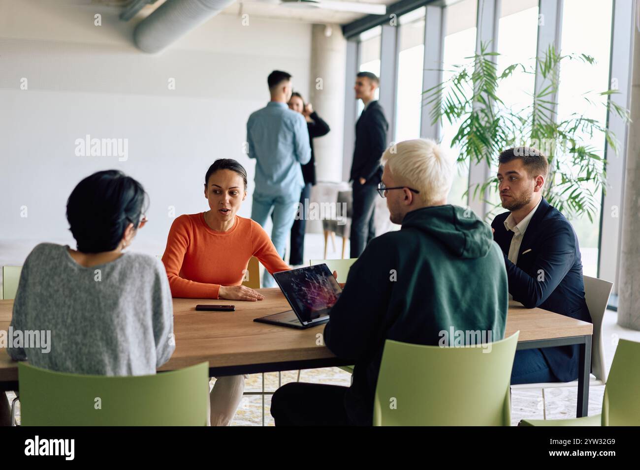 A diverse team of business professionals engaged in a discussion around ...