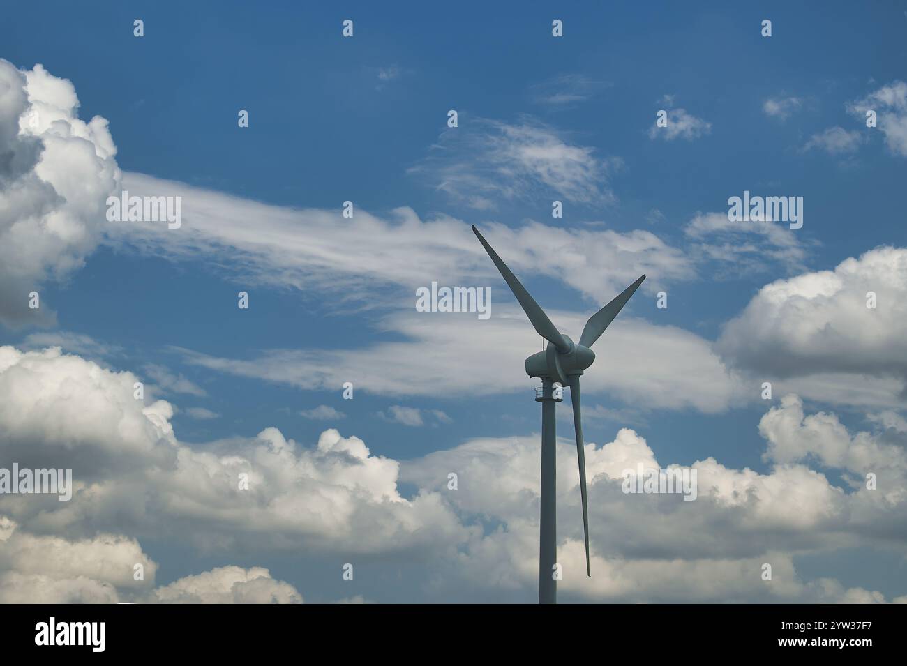 Wind turbine standing tall against a mix of cloudy and clear blue sky ...