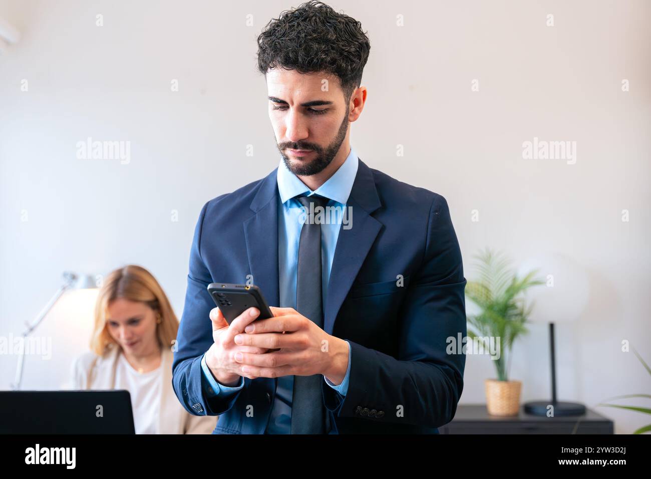Focused Businessman Using Smartphone in Modern Office Setting Stock Photo