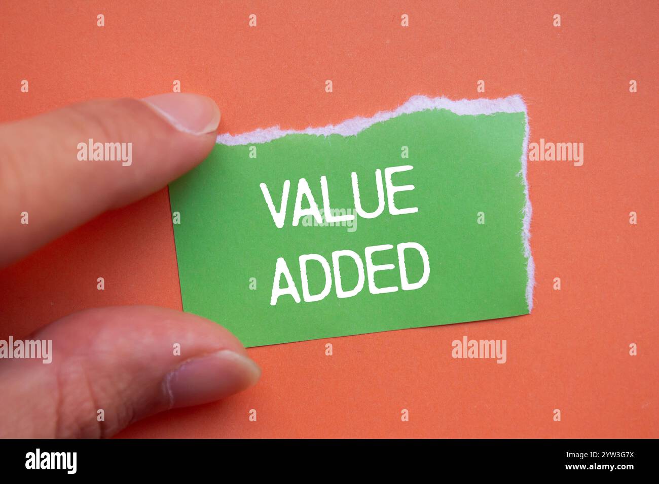 Value added message written on ripped green torn paper with orange ...