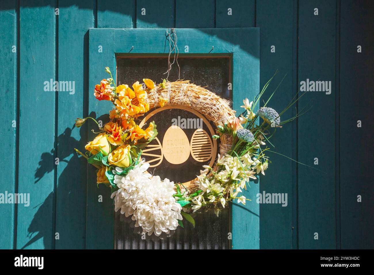 Floral wreath with Easter eggs and the inscription “Happy Easter� on a wooden door, Germany Stock Photo