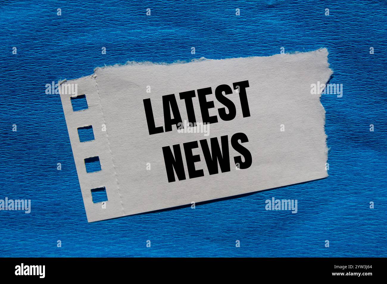 Latest news message written on ripped torn paper piece with blue ...