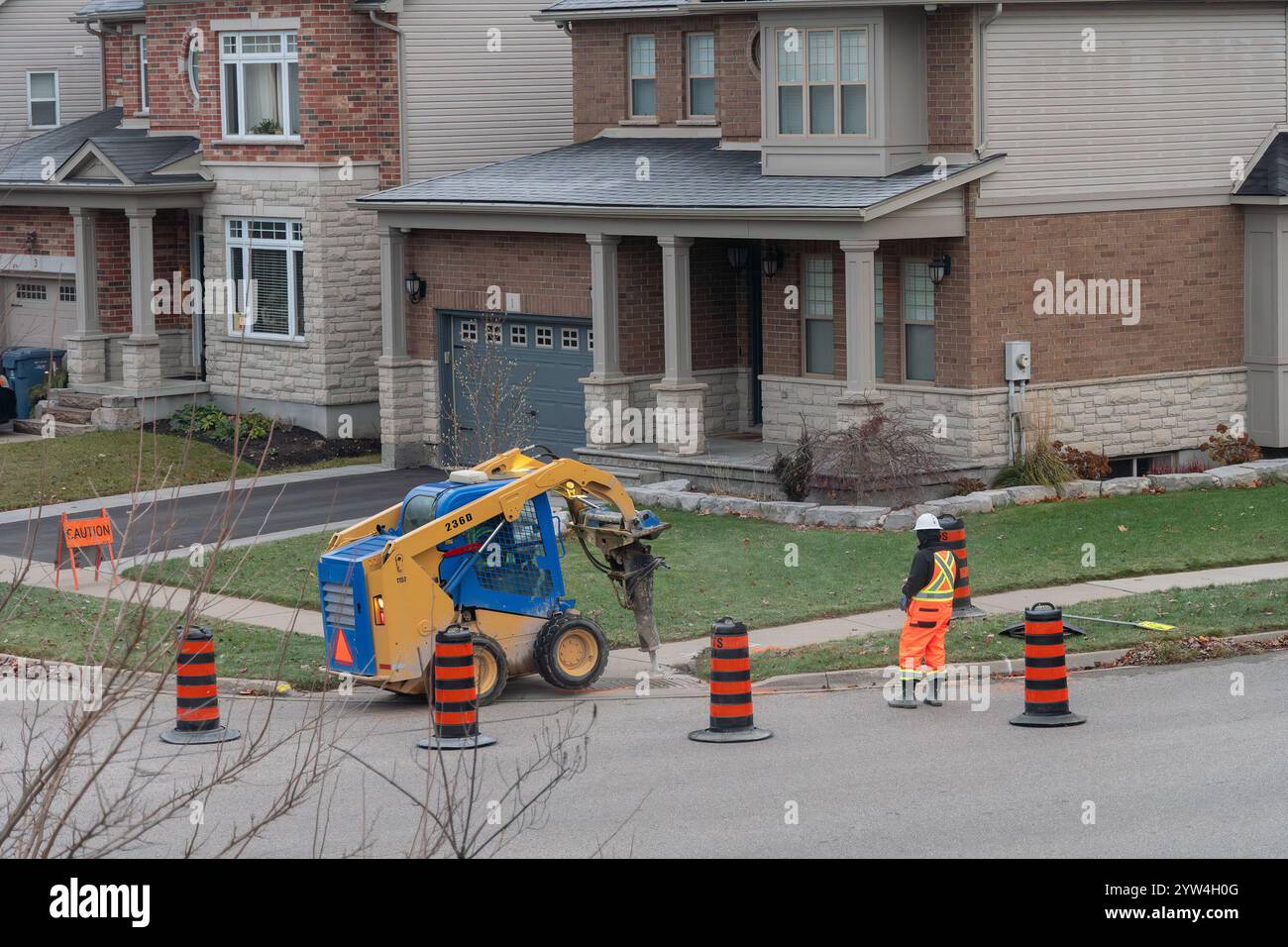 A small tractor with a chisel breaks a concrete slab on the sidewalk to ...