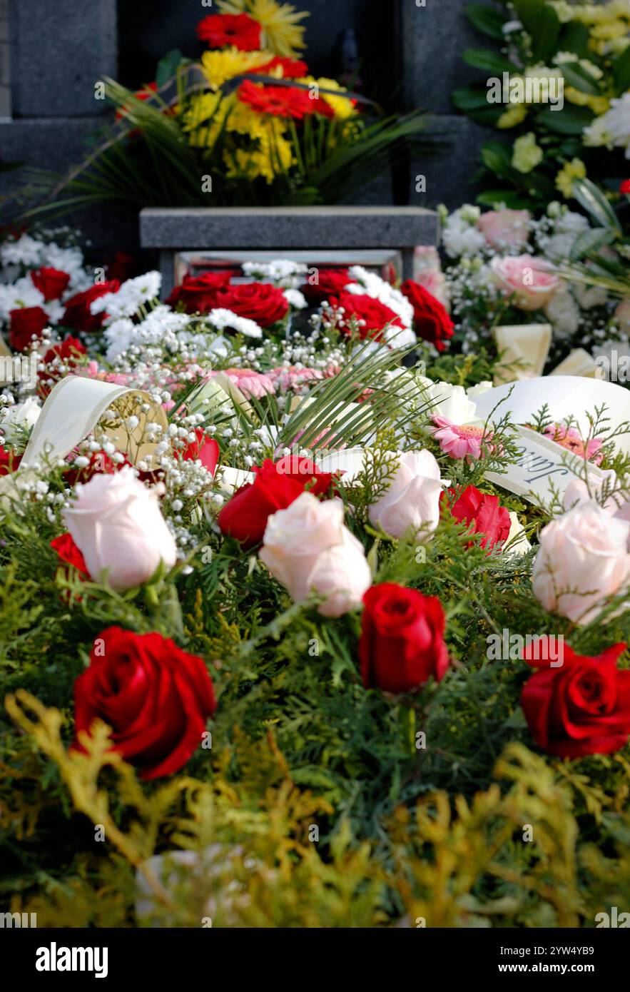 Close up of fresh floral wreaths made of red and pink roses on the grave after a funeral. Funeral wreaths at a cemetery in the Czech Republic. Stock Photo