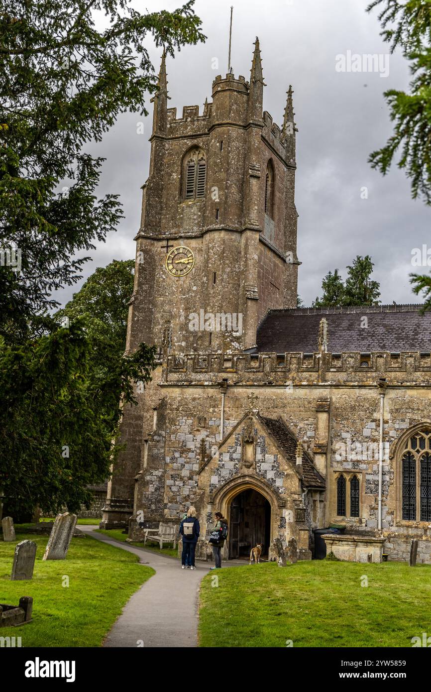 Avebury, UK- August 25, 2024: Avebury Church dates from the year 1000 AD and is situated near Avebury Manor in Wiltshire. a woman sits on a bench besi Stock Photo