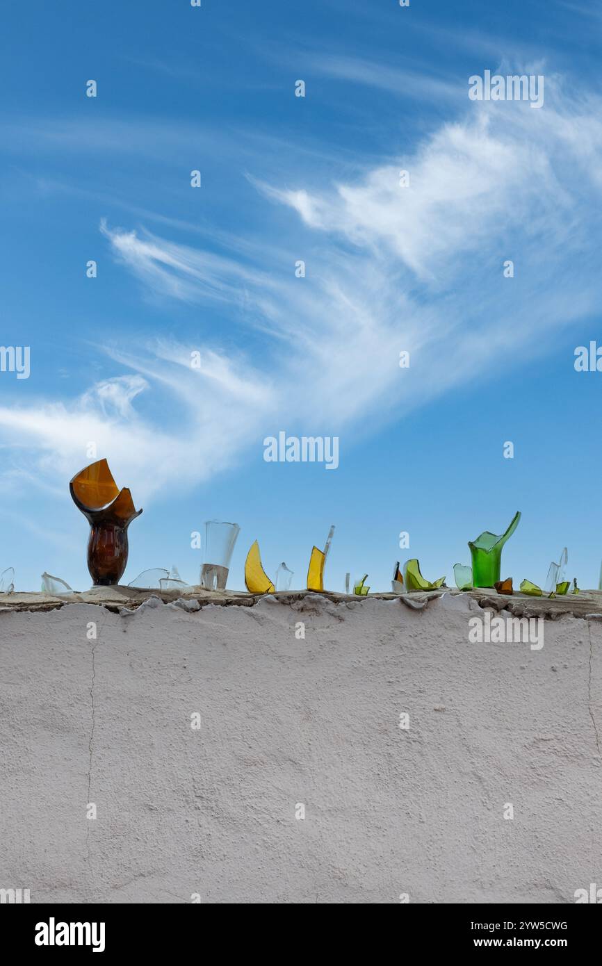 Broken glass bottles on perimeter wall of large house Stock Photo