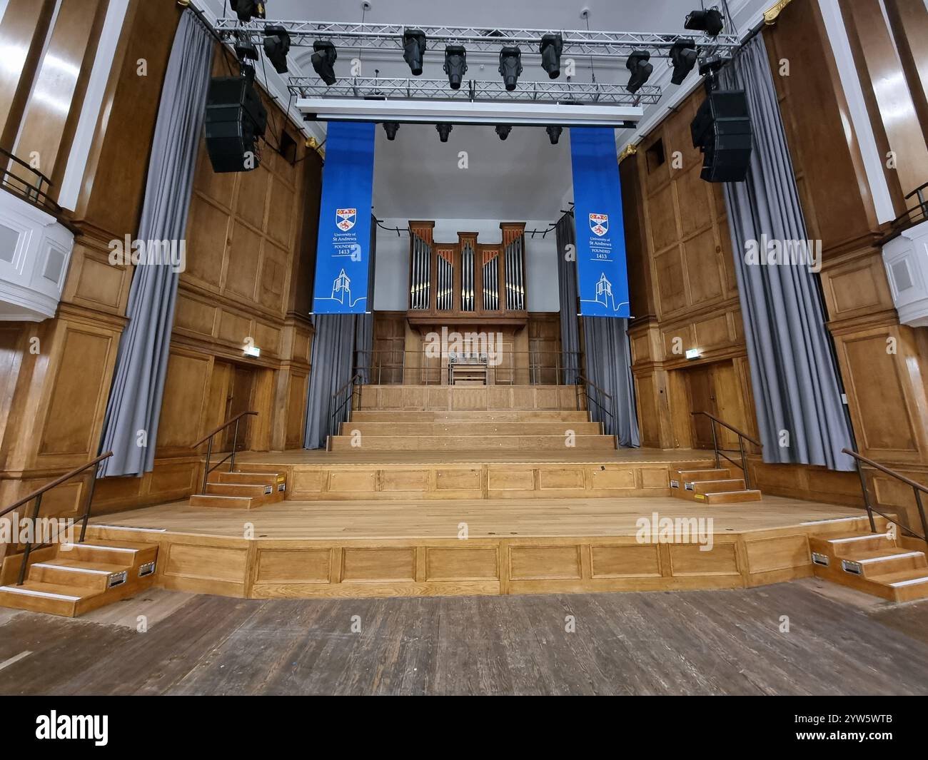 Stage in interior of the Younger Hall at North Street, St Andrews, Scotland, UK, with organ; blue banners with logo of University of St Andrews - Smartphone Captured Stock Image