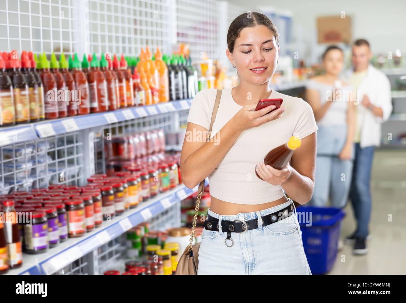 Girl reads a QR code from a bottle of hot sauce in chinese supermarket ...
