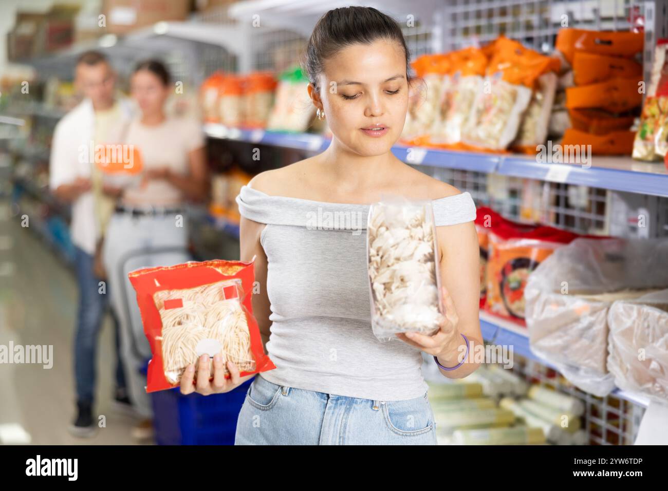 Young Asian woman choosing noodles in grocery section of supermarket ...