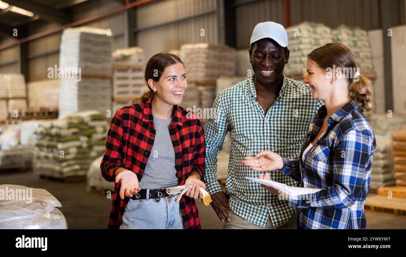 Workers and manager discussing completed work in large warehouse Stock Photo