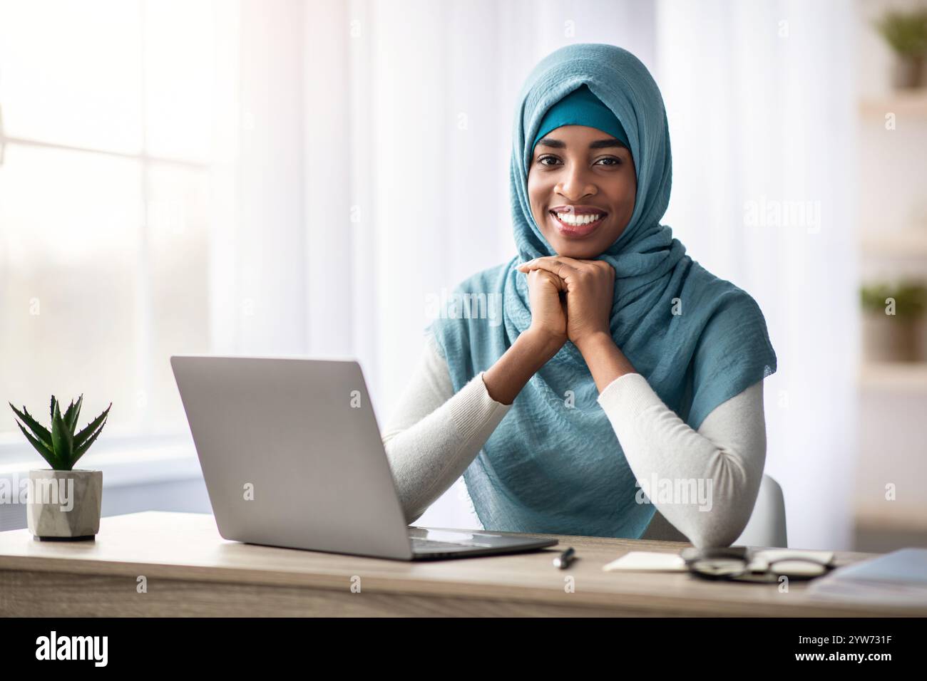 Happy Smiling Black Muslim Lady In Hijab Sitting At Desk With Laptop ...