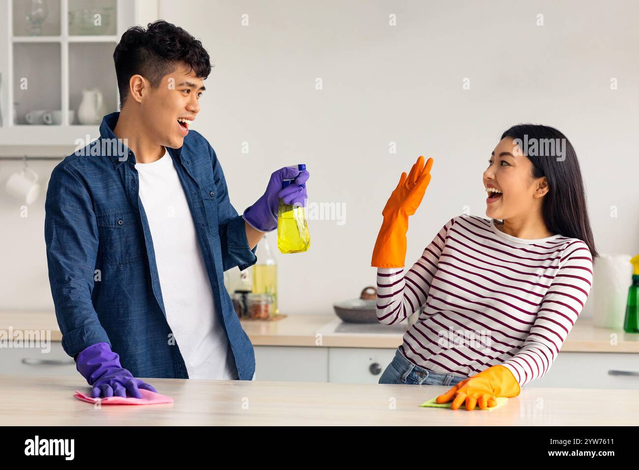 Joyful asian lovers having fun while cleaning kitchen together Stock Photo