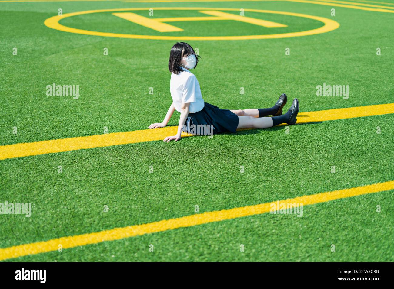 Female student sitting on lawn Stock Photo - Alamy