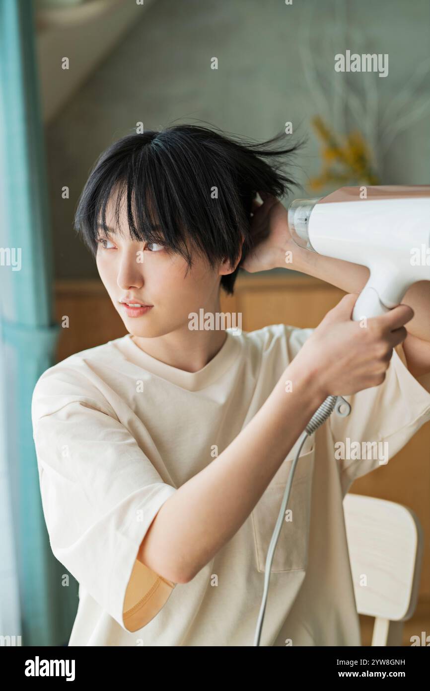 Woman drying her hair with a hairdryer Stock Photo - Alamy