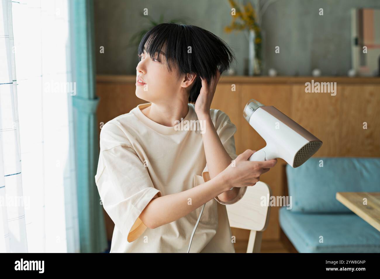 Woman drying her hair with a hairdryer Stock Photo - Alamy