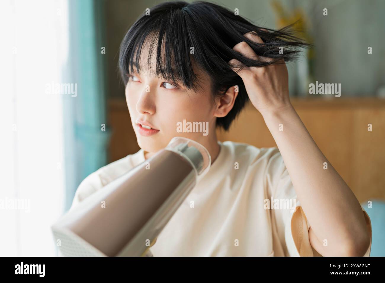Woman drying her hair with a hairdryer Stock Photo - Alamy