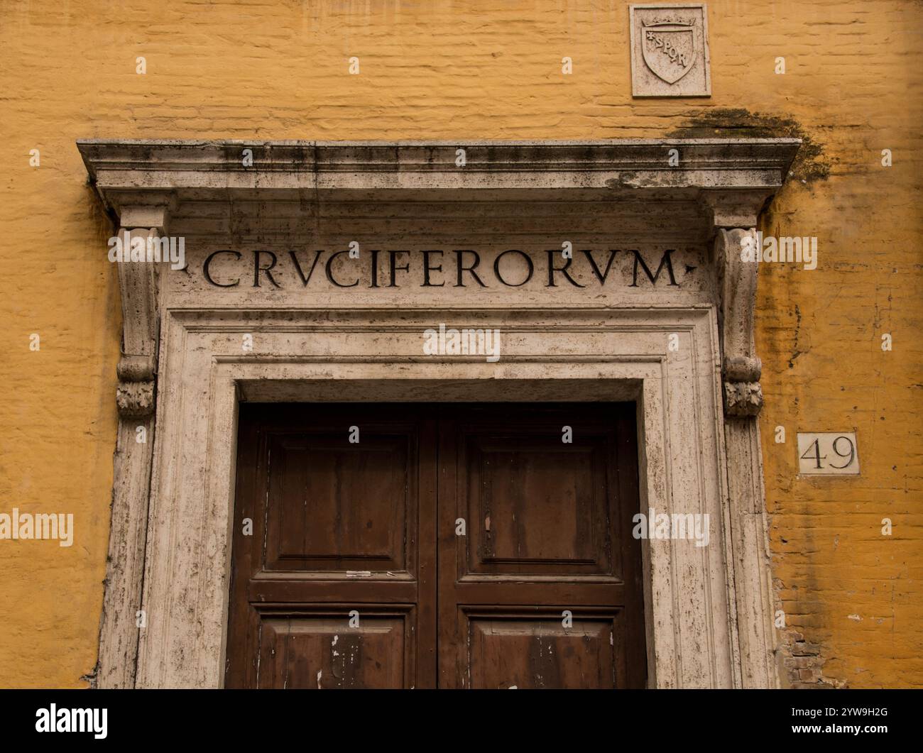 Open Roman Lettering An old doorway, set in an ochre coloured wall, with roman lettering ...