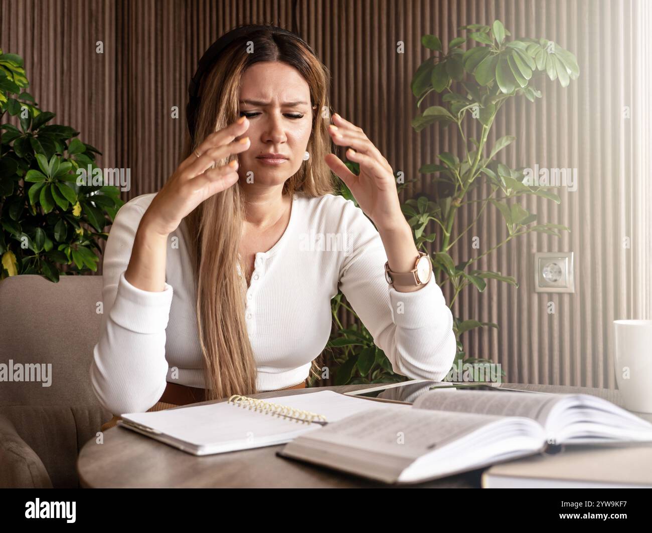 Woman with long blonde hair wearing headphones, sitting at table with ...