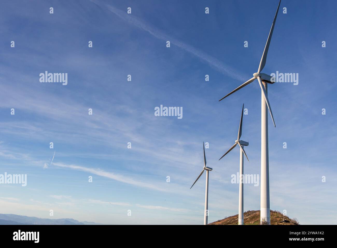 Picture of Three wind turbines are standing tall on a mountain top, generating ...