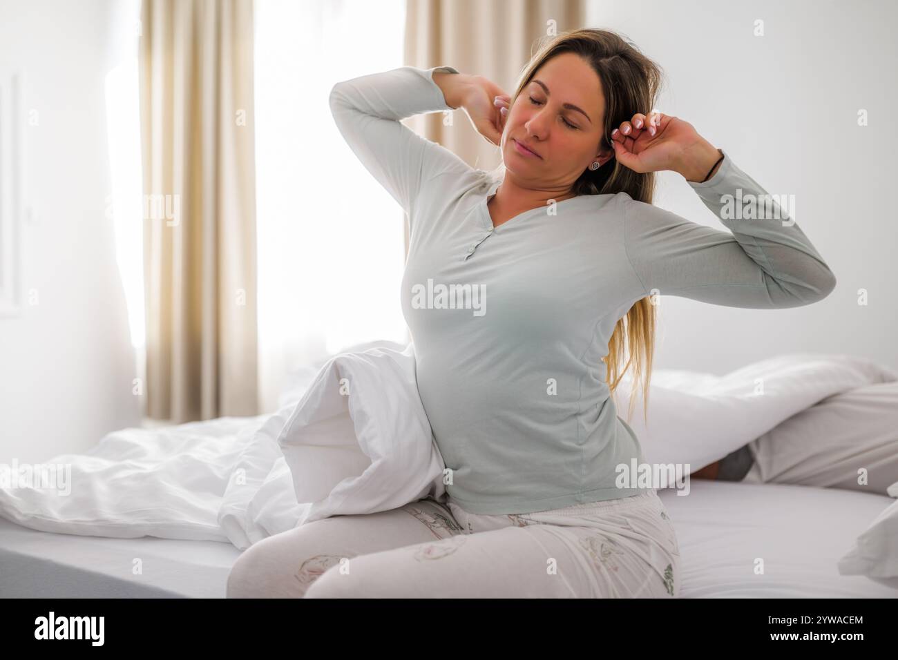 Young couple is sleeping in bed. Woman is waking up for work. Stock Photo