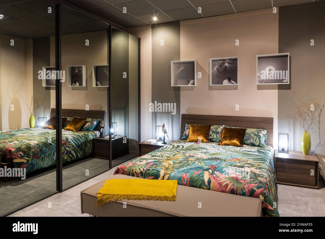 Modern bedroom showcasing stylish furniture, tropical themed bedding, and a mirrored closet, creating a vibrant and sophisticated ambiance Stock Photo