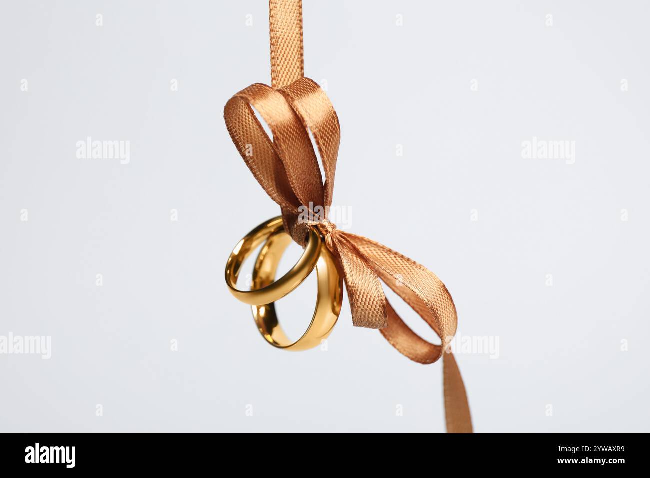 Wedding rings tied with ribbon against light grey background, closeup ...