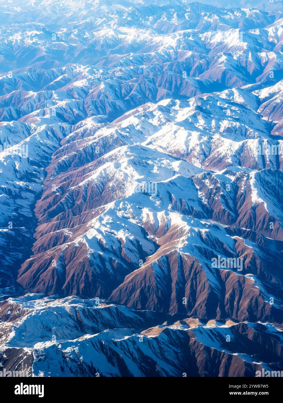 above view of snowy tops of Caucasus mountains through window of flying airplane on sunny autumn day Stock Photo