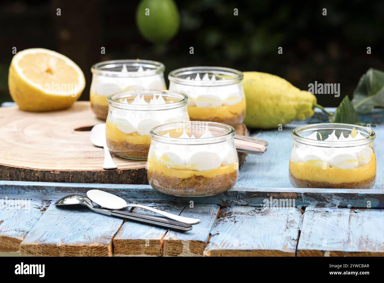 Close-up of individual servings of lemon meringue pies on a wooden chopping board with fresh lemons Stock Photo