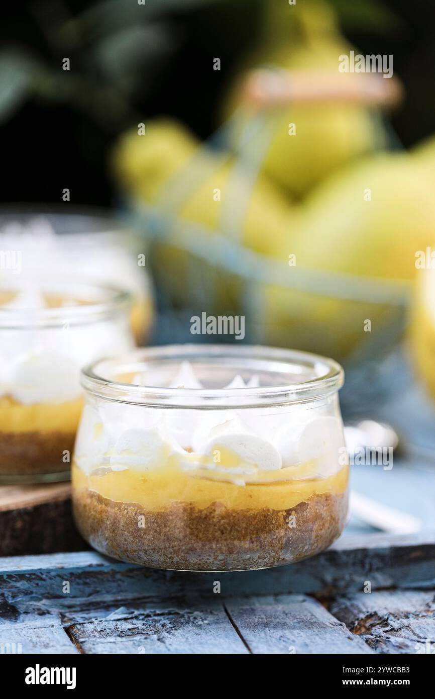 Close-up of individual servings of lemon meringue pies on a wooden chopping board with fresh lemons Stock Photo