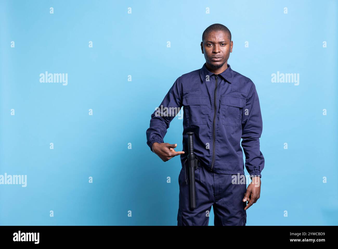 Male security guard pointing to his baton to ensure protection on duty ...