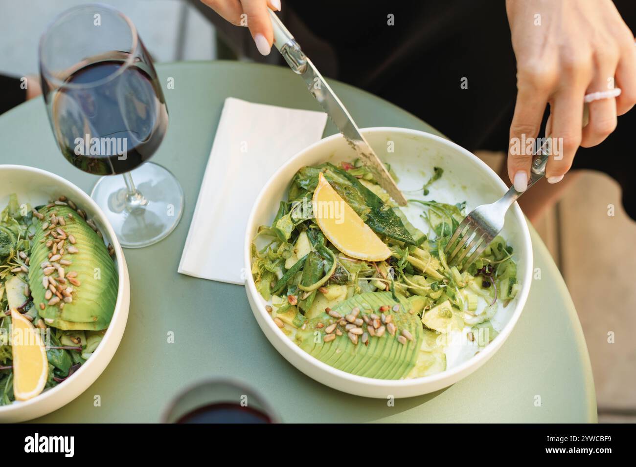 Overhead view of a woman eating a green salad with avocado, cucumber and toasted sunflower seeds Stock Photo