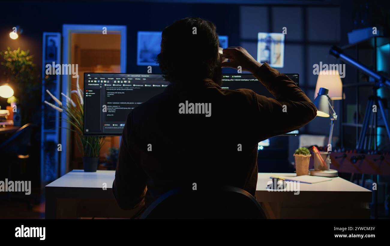 Software engineer writes complex binary code scripts on computer, close up. Teleworking IT specialist in home office using programming to safeguard consumer data, handheld camera shot, camera B Stock Photo