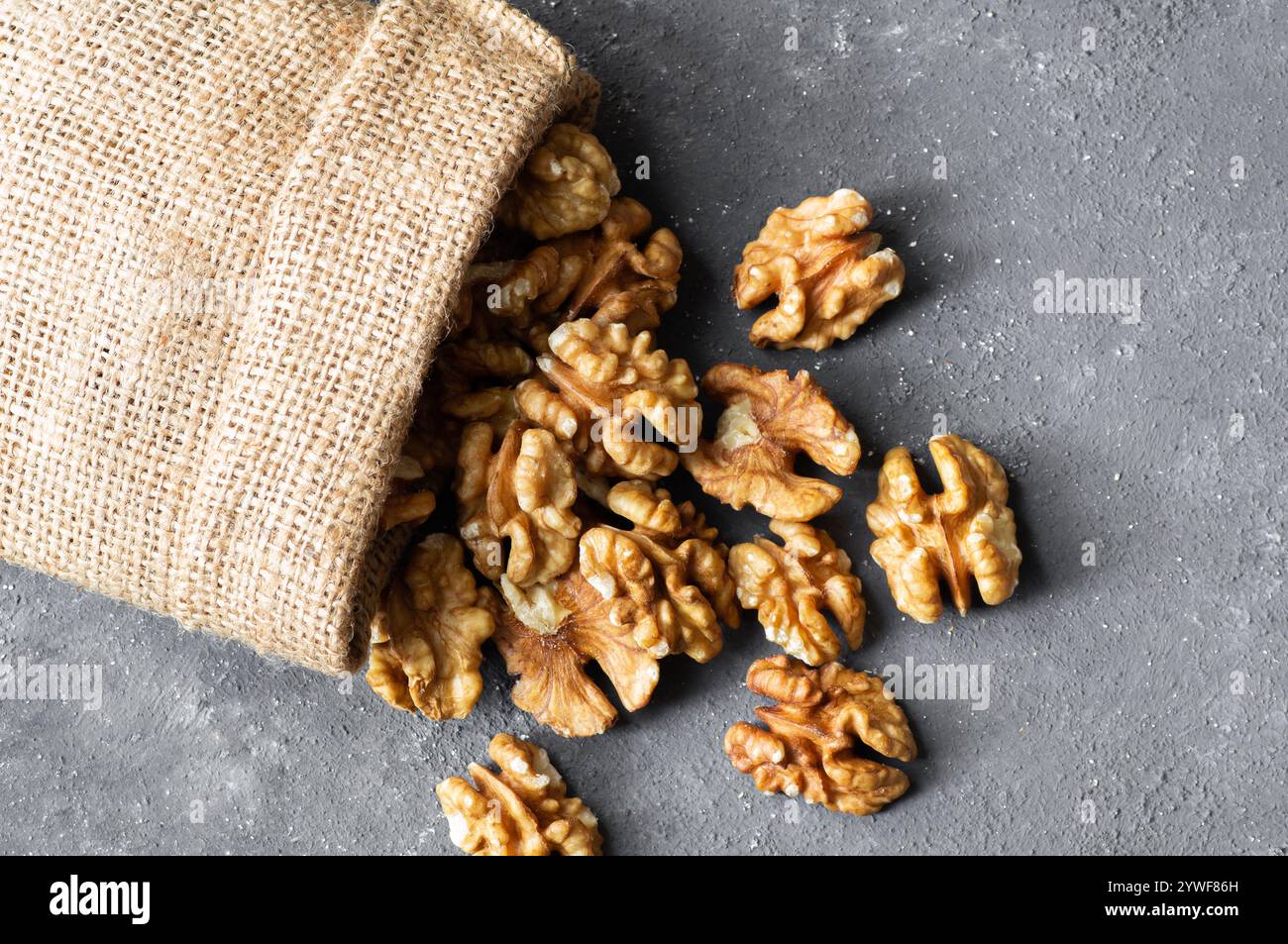 Ripe and fresh walnut kernels in bowl or burlap sack without shell on rustic table, healthy nut food for brain Stock Photo