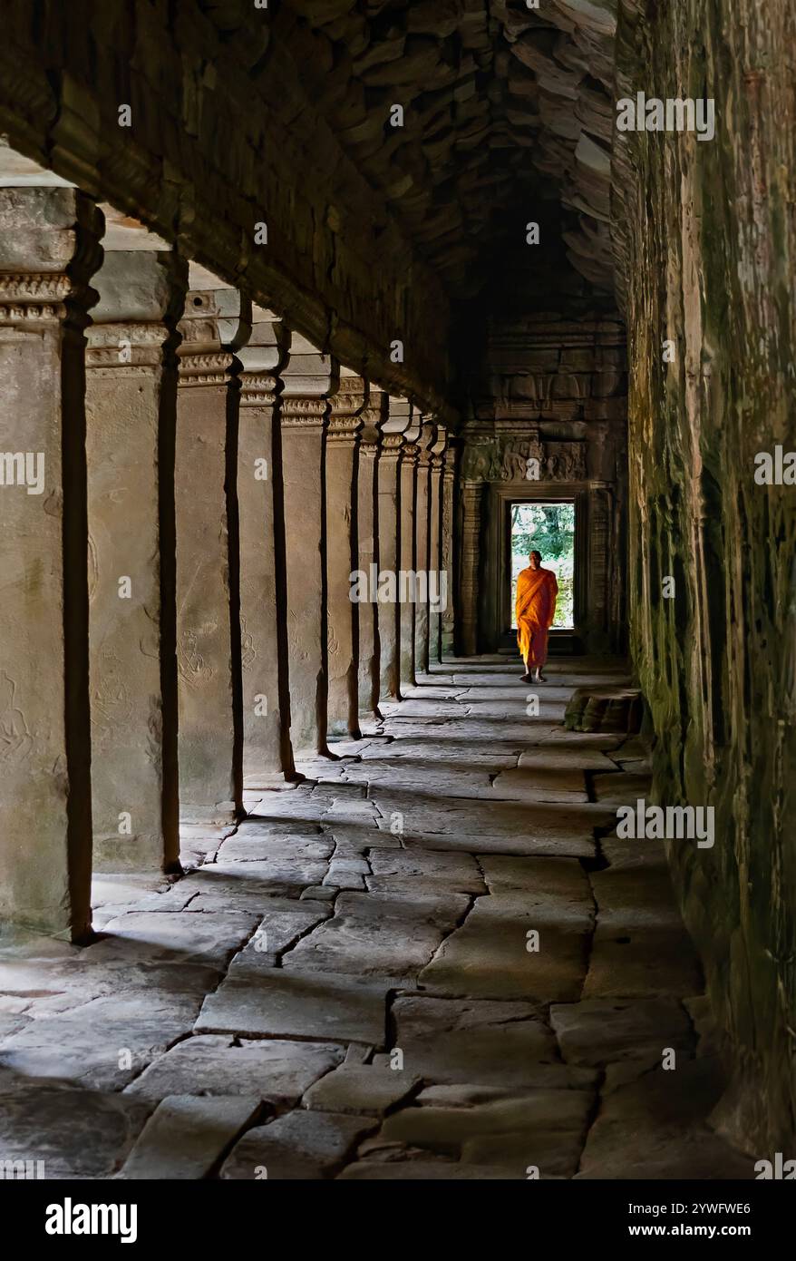 Buddhist monk walking in the colonnade of the Ta Prohm temple in Siem Reap, Cambodia Stock Photo