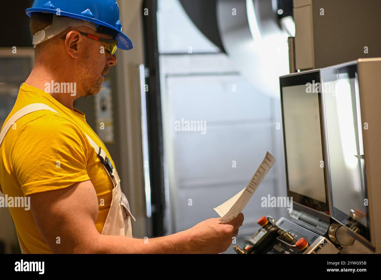 Industrial engineer managing a cnc milling machine using a computer ...