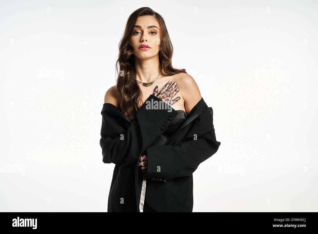 Young woman poses confidently in a black oversized coat, highlighting her stylish hand tattoos. Stock Photo