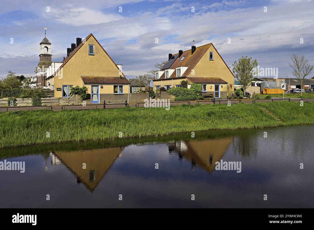 Typical houses reflected in the pond behind Wadden Church, (Waddenkerk), De Cocksdorp, Texel, Holland, Netherlands Stock Photo
