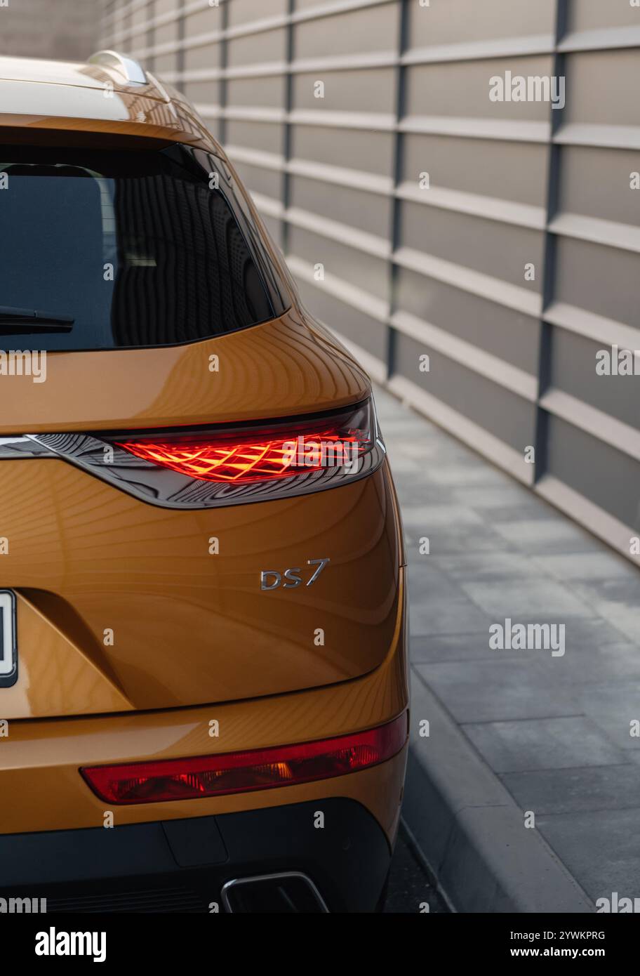 Orange DS7 parked near dark grey wall with horizontal bars. Rear right ...