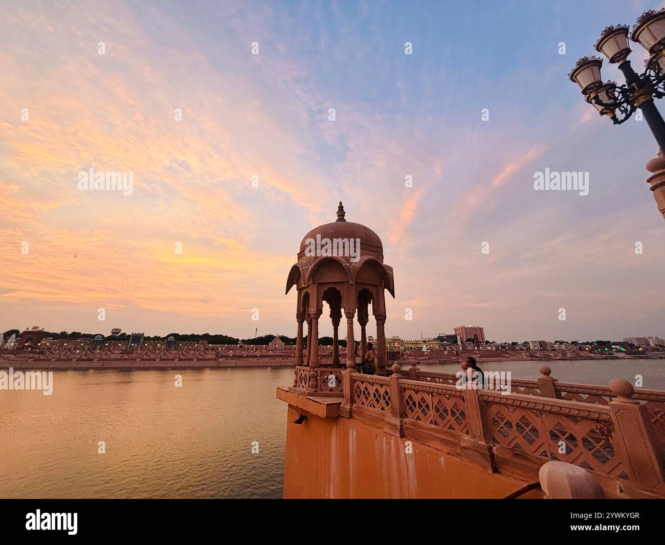 An ancient architect stands proudly against a breathtaking sky, the golden hues of sunset casting a warm glow on his weathered face. - Smartphone Captured Stock Image