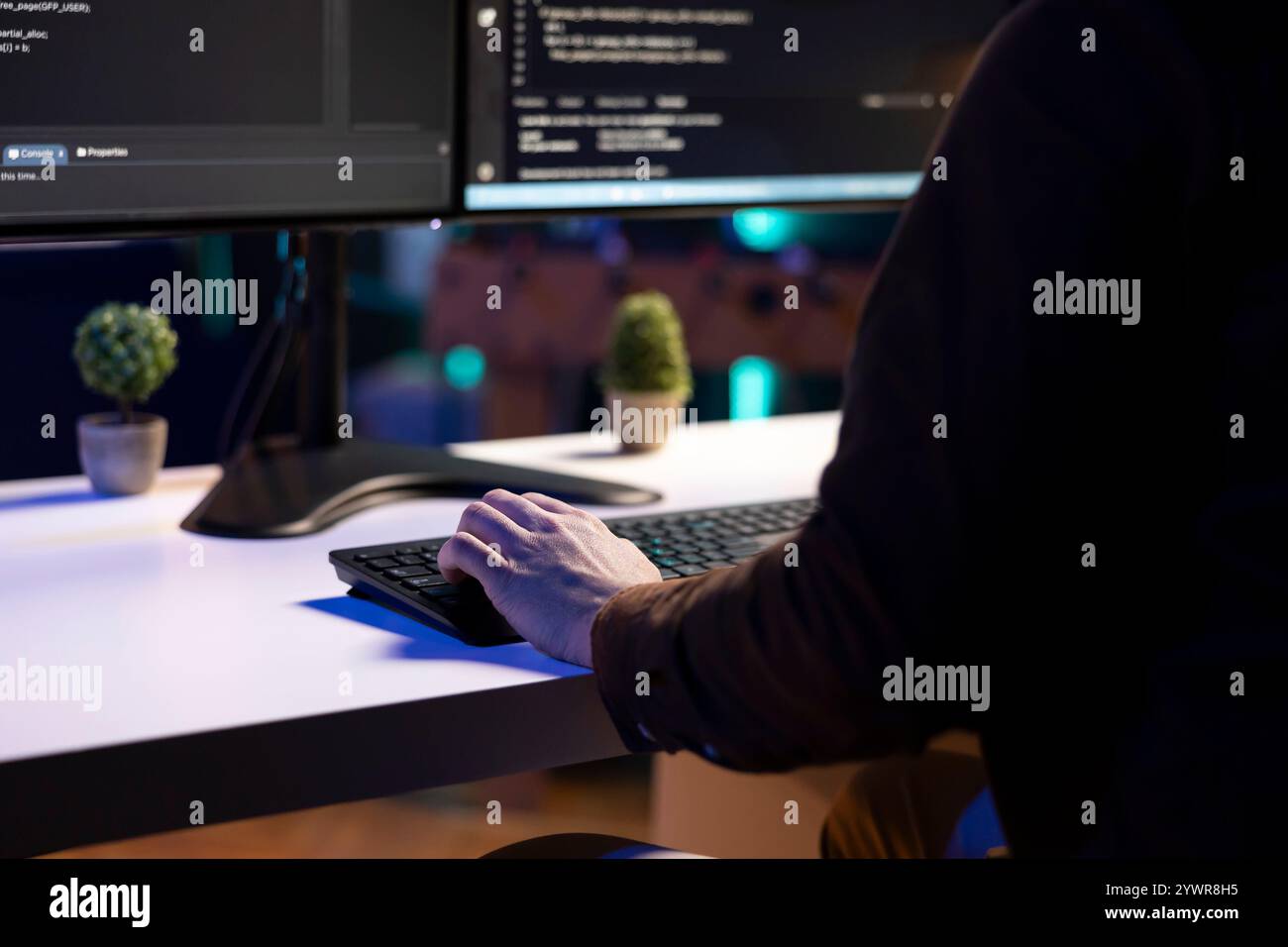 Freelancing programmer doing software debugging on computer at home, checking flaws in lines of code displayed on monitors. IT admin in apartment fixing coding issues, typing on keyboard, close up Stock Photo