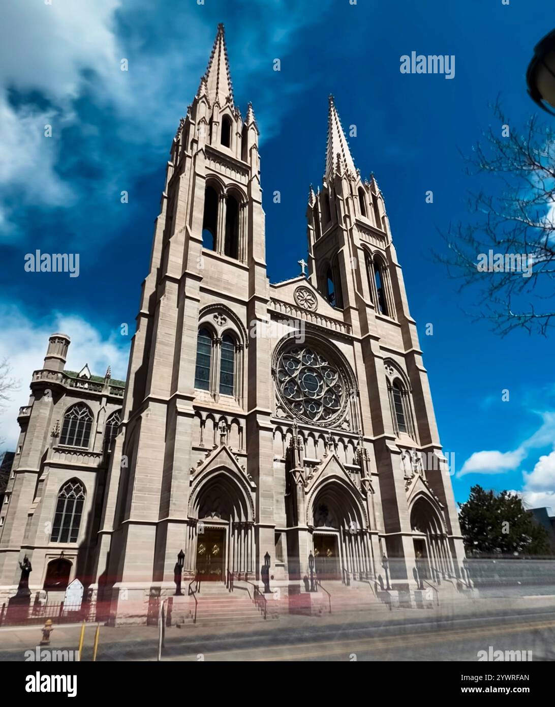 The image showcases a magnificent Gothic-style church standing tall against a vivid blue sky. The church features intricate stonework, pointed arches, - Smartphone Captured Stock Image
