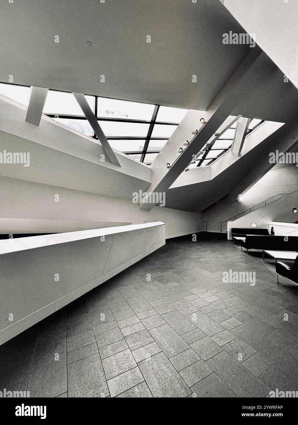 The interior of the white building is bright and open, with sunlight streaming through large windows set into the ceiling. - Smartphone Captured Stock Image
