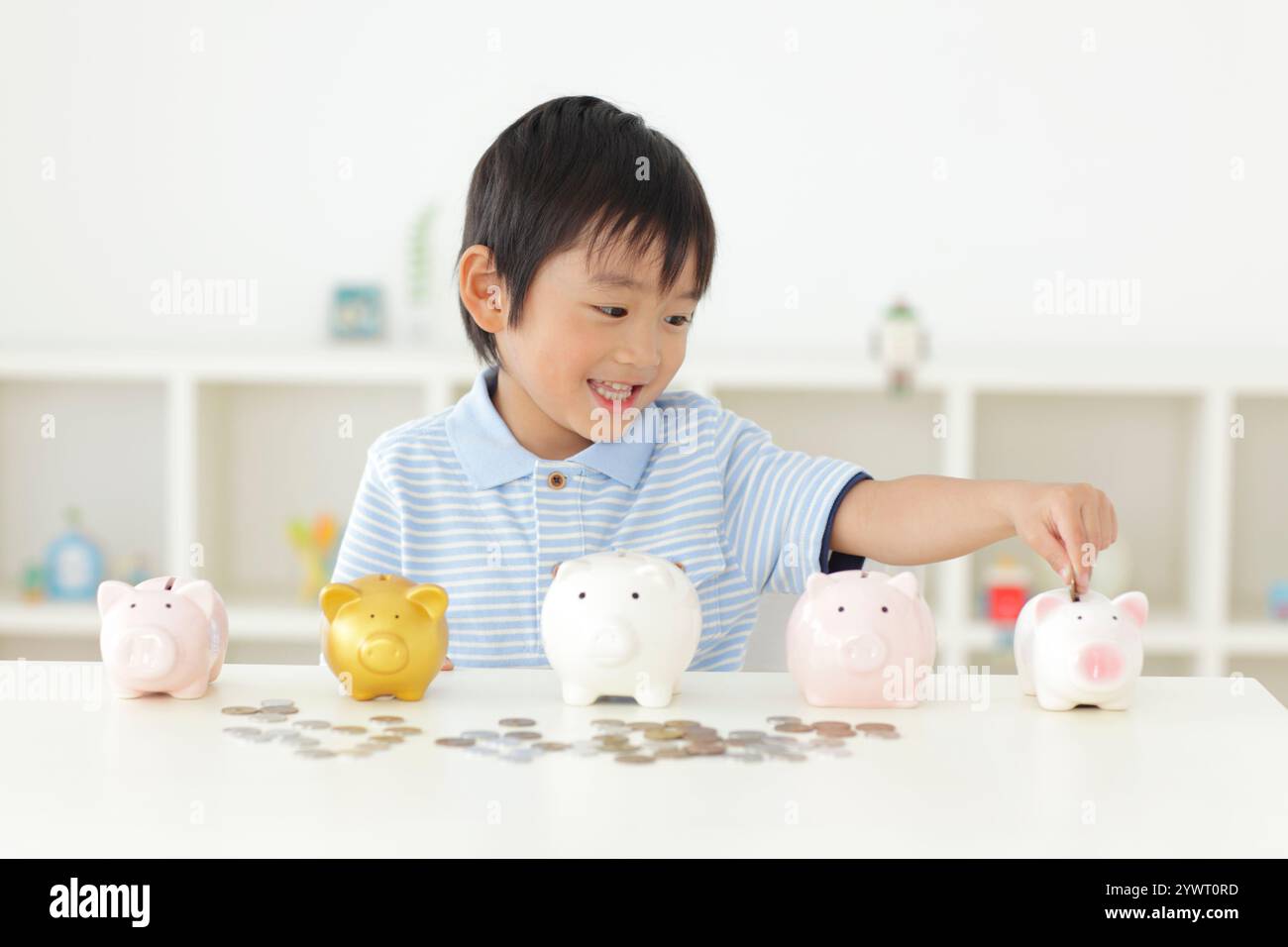 Boy putting money into piggy bank Stock Photo - Alamy