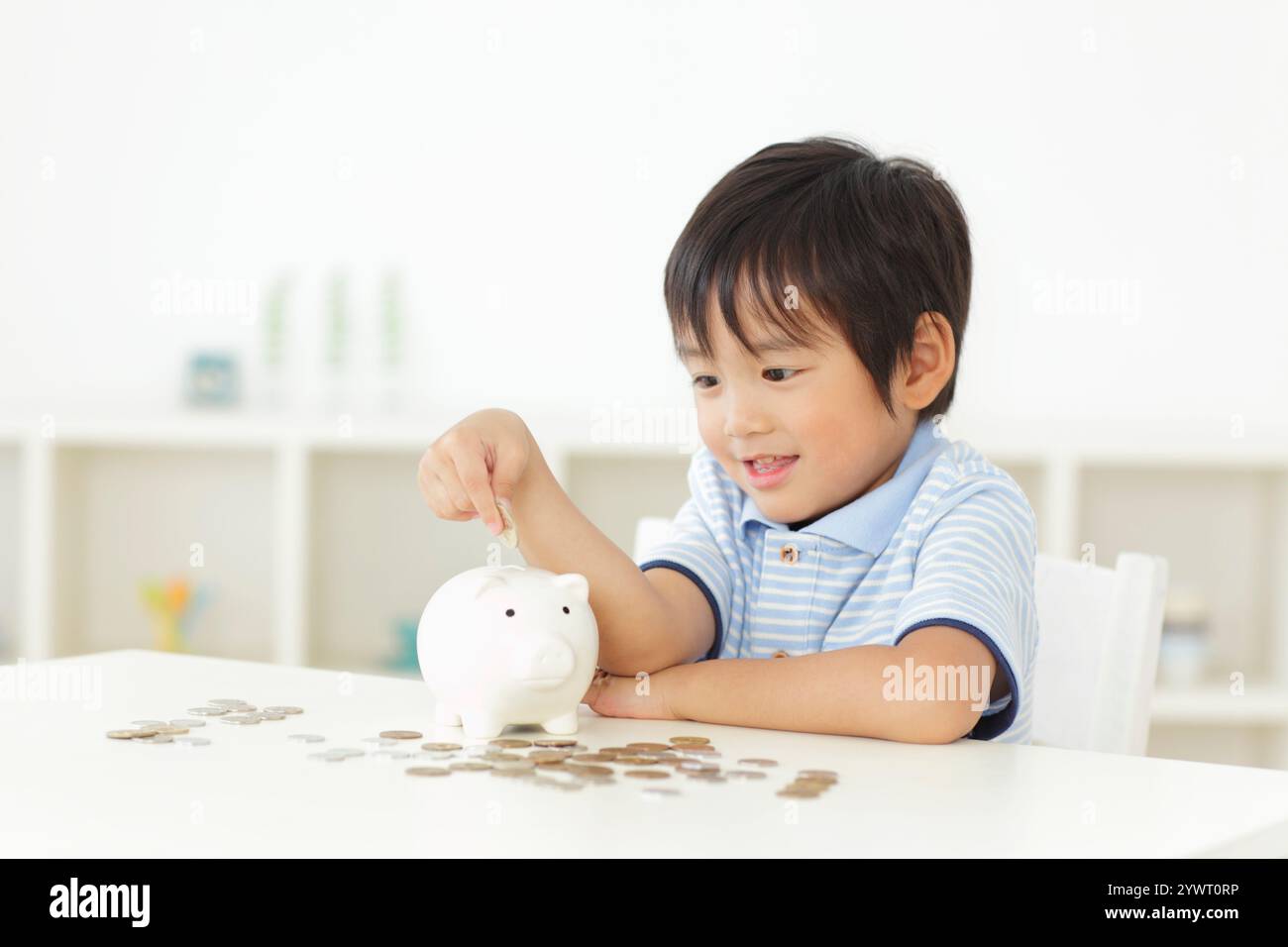 Boy putting money into piggy bank Stock Photo - Alamy