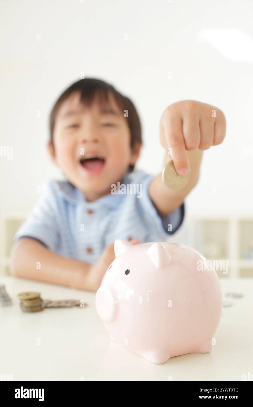 Boy putting money into piggy bank Stock Photo - Alamy