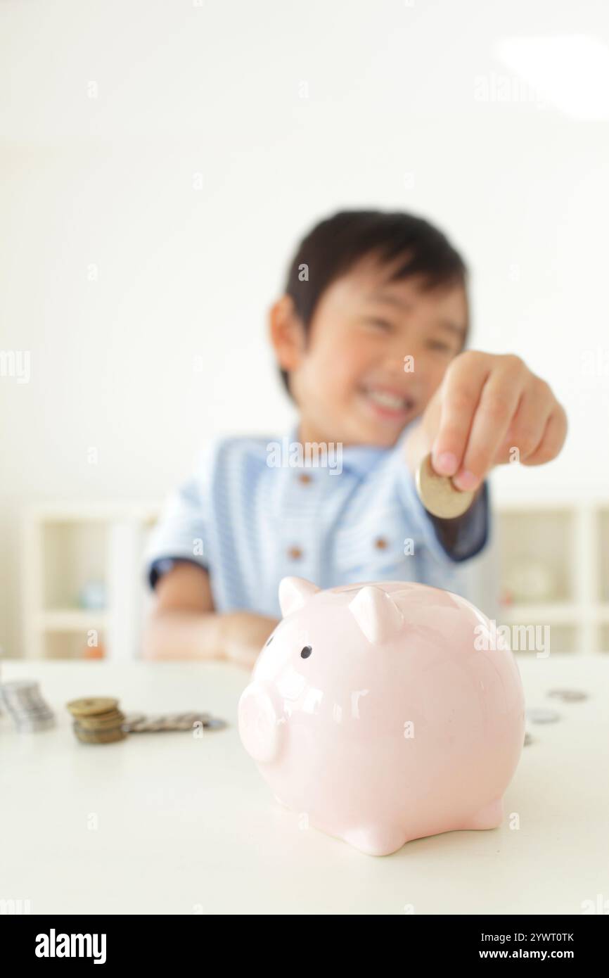 Boy putting money into piggy bank Stock Photo - Alamy