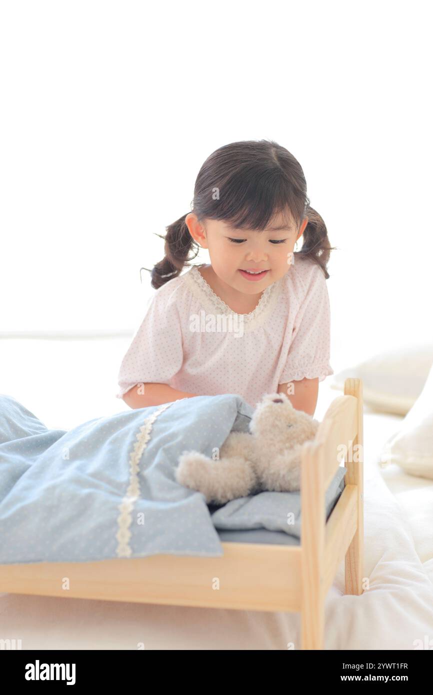 Girl playing with stuffed animal on toy bed Stock Photo - Alamy