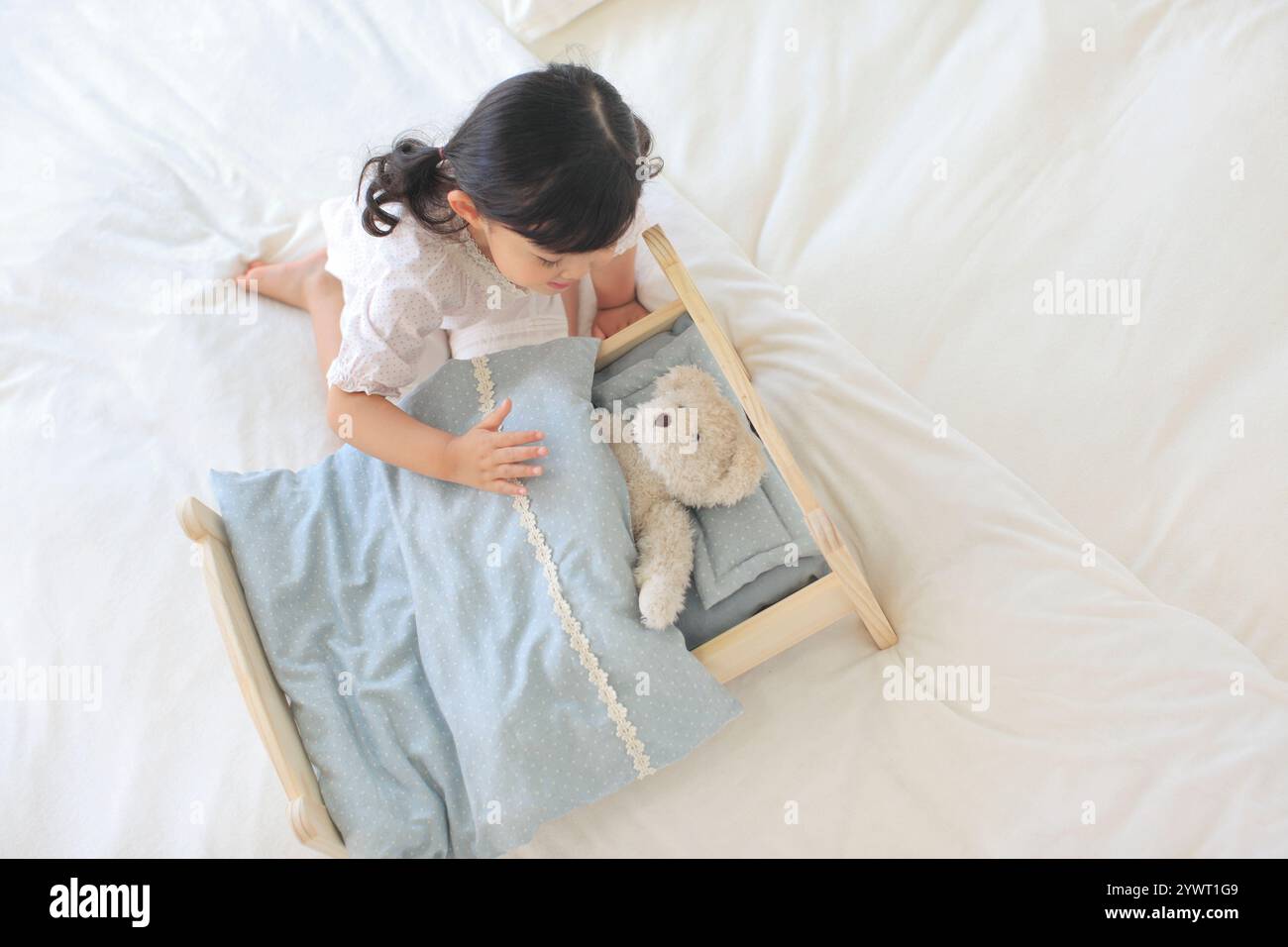 Girl playing with stuffed animal on toy bed Stock Photo - Alamy